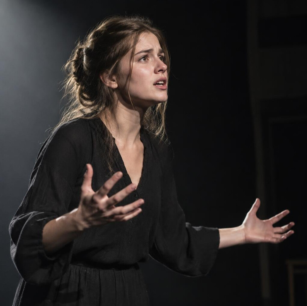 Student performing a dramatic monologue under stage lighting